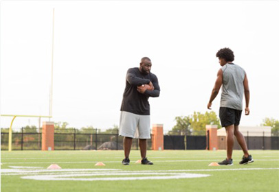 Football coach mentors athlete after practice. Premier Sport Psychology offers team and organization sessions to optimize group performance .