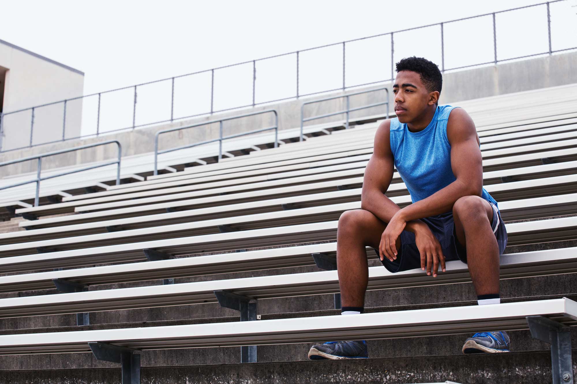 Young track athlete sits on bleachers, lost in thought. Inattention is a common symptom in those suffering from ADHD. Testing can diagnose whether these symptoms are chronic, and can give individuals treatments and skills to manage attention deficits.