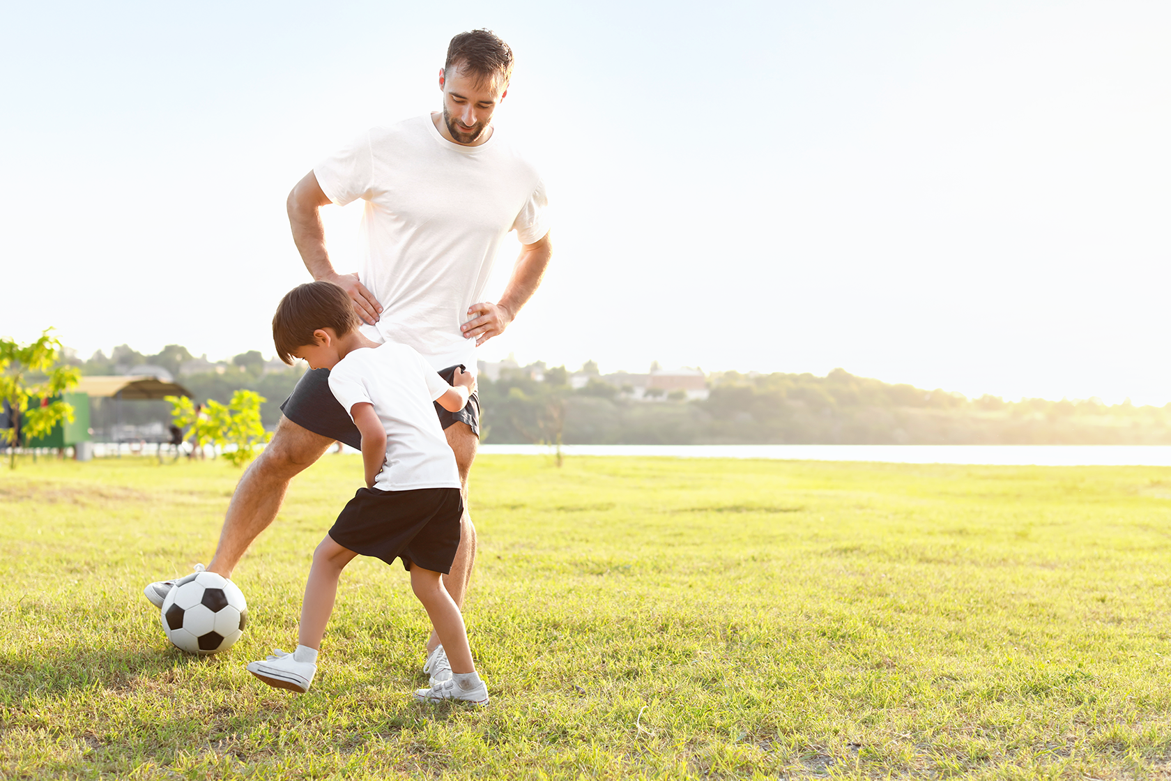 Father and young son play soccer in the sun. Sport Psychology services can help parents deliver life affirming sport experiences for their children. Click image to learn more.